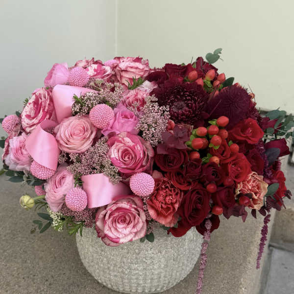 Pink and red rose arrangement in a textured stone vase