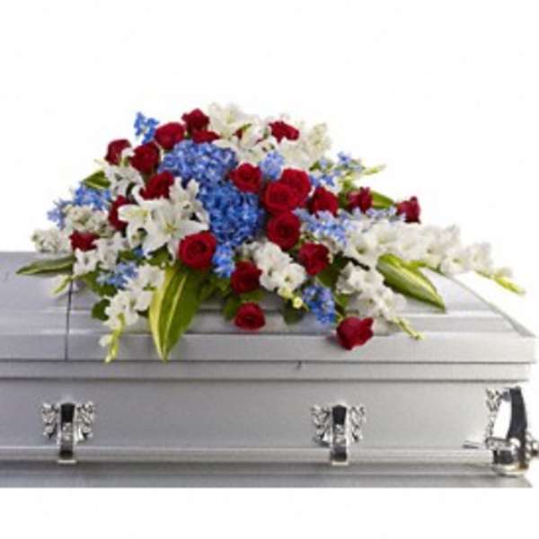 Red, white, and blue floral spray on a silver casket