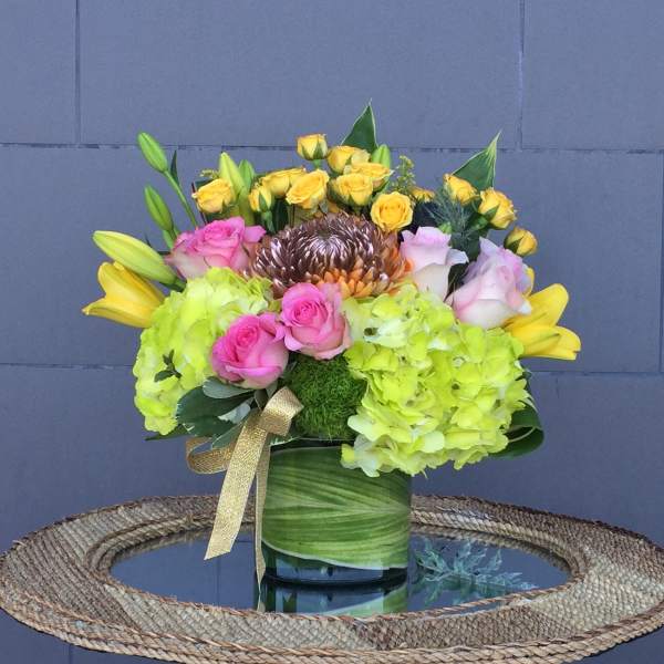 Bouquet of yellow and pink roses with lime hydrangeas in a green vase