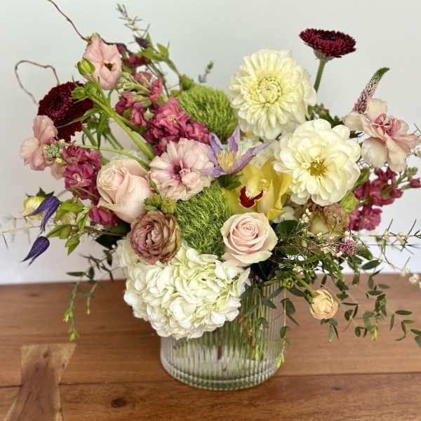 Mixed bouquet of pink, white, and yellow flowers in a glass vase