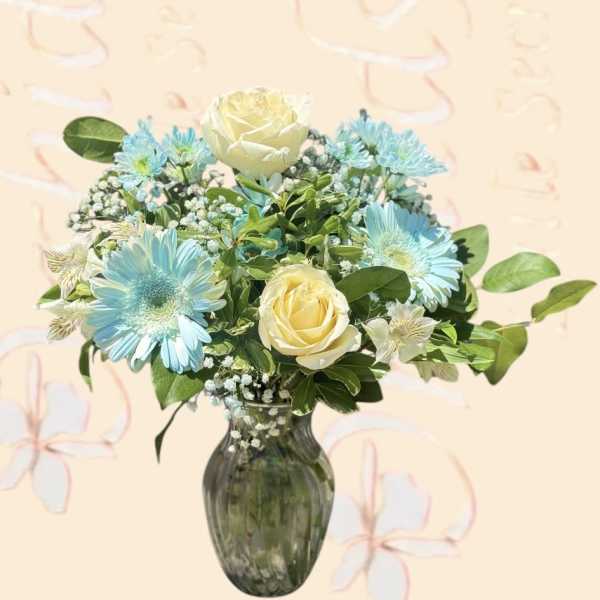 Blue daisies and cream roses arranged in a glass vase