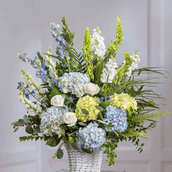 Blue and white floral arrangement in a white wicker basket