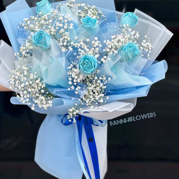 Bouquet of blue roses and white baby's breath wrapped in pale blue paper