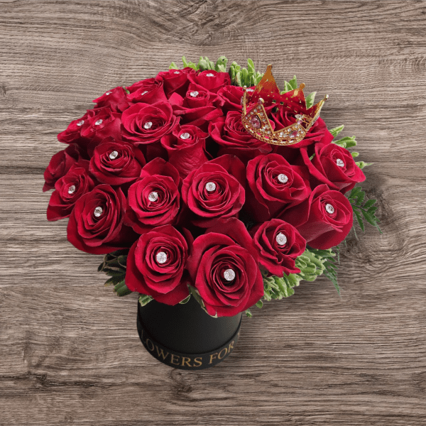 Red rose bouquet in a black hatbox with a small crown topper