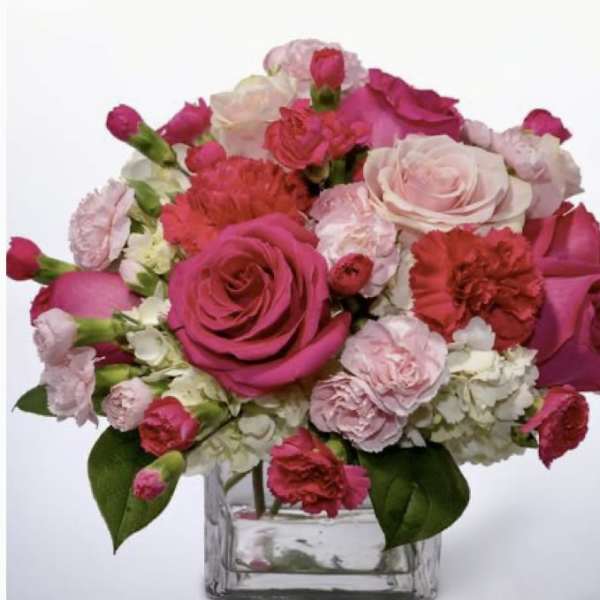 Pink and white roses with carnations in a clear glass vase