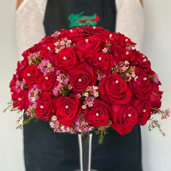 Red rose bouquet with pink filler flowers in a clear glass vase