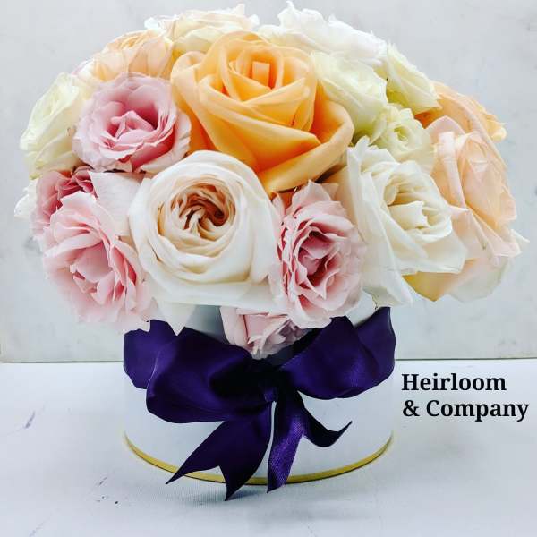 Bouquet of pastel roses in a white hat box with a purple ribbon