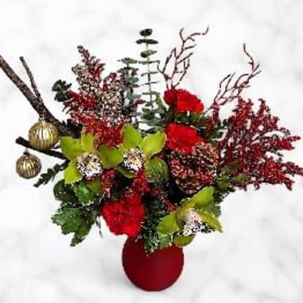 Red floral arrangement in a red vase with gold ornaments and branches