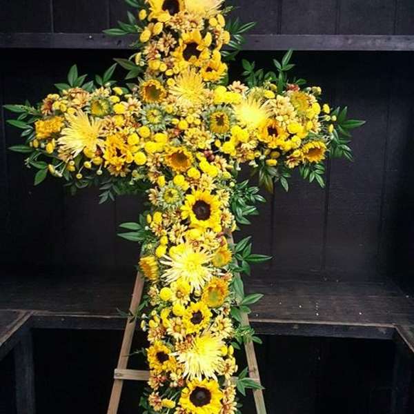 Yellow floral cross on a wooden stand
