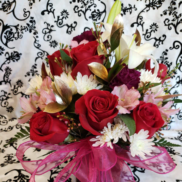 Bouquet of red roses, white lilies, and pink flowers with a pink ribbon