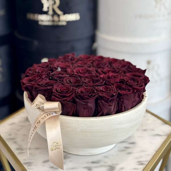 Round box of deep burgundy roses with a ribbon bow