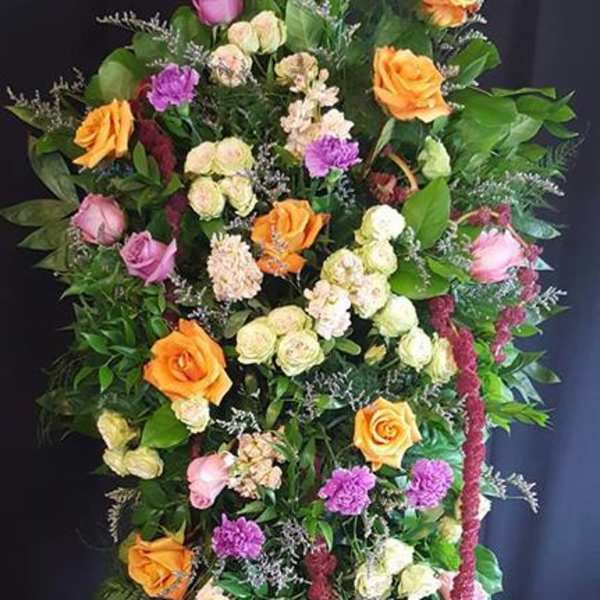 Tall standing floral spray with roses in pink, orange, and cream