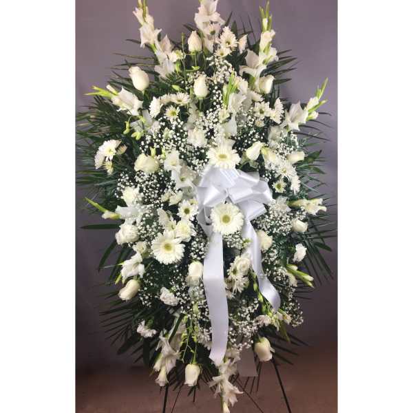 White funeral spray with lilies, daisies, and a white ribbon on an easel