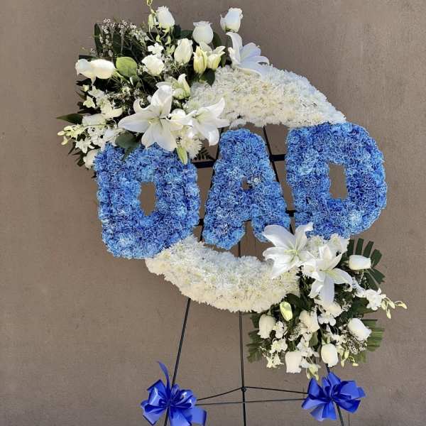 Floral standing tribute spelling DAD with blue and white flowers