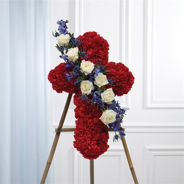 Red floral cross on a stand with white roses and blue flowers