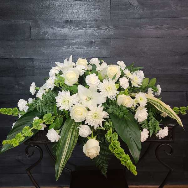 White floral casket spray with roses and lilies