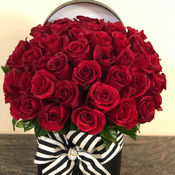 Red rose arrangement in a black box with a striped ribbon