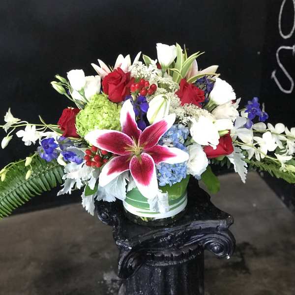 Mixed bouquet with red roses, white lilies, and a pink stargazer lily in a vase