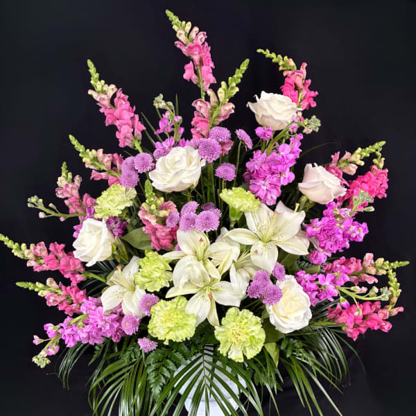 Pink and white floral arrangement with lilies, roses, and snapdragons