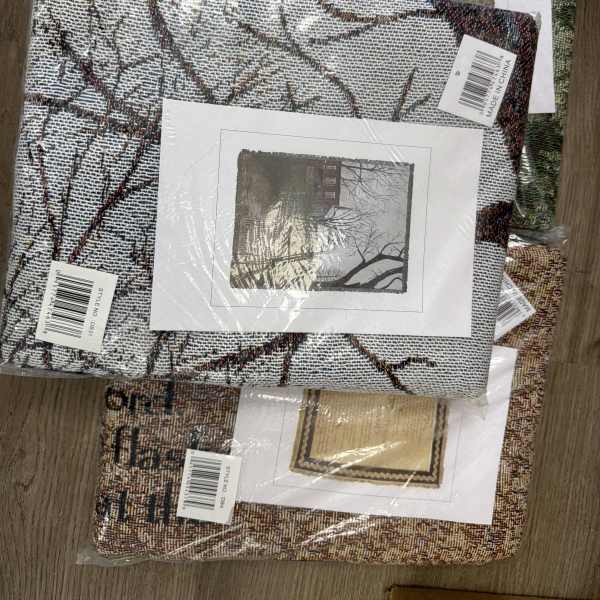 Stack of packaged woven decorative textiles with printed scene inserts