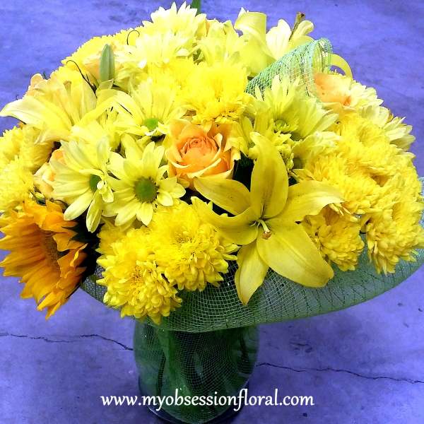Yellow bouquet with daisies, chrysanthemums, and roses in a glass vase