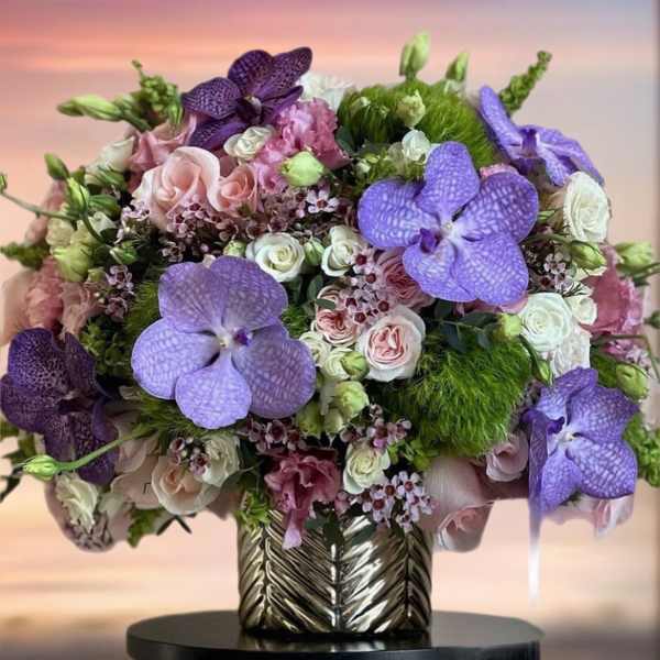 Bouquet of purple orchids and pink roses in a metallic vase