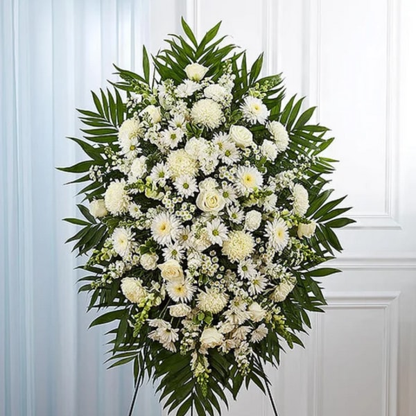 White funeral spray with daisies and roses on a stand