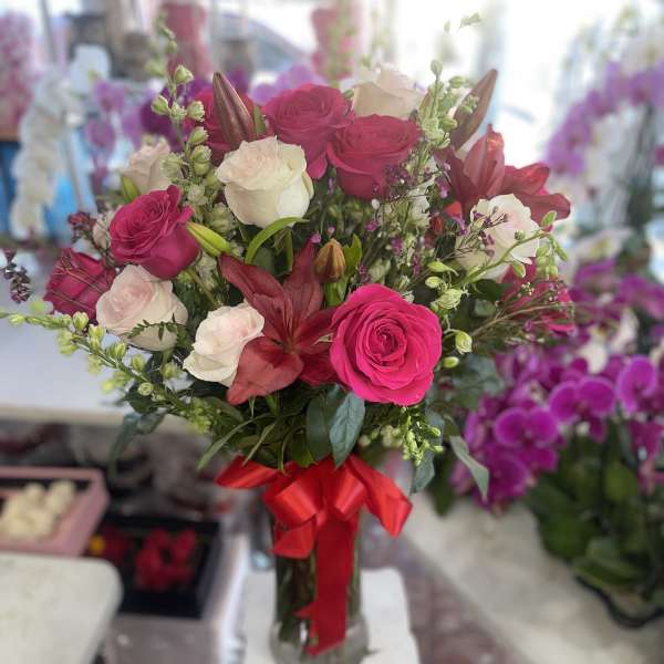 Bouquet of pink and white roses with red lilies in a glass vase