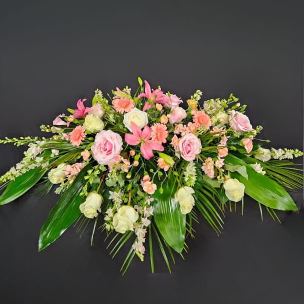 Pink and white floral spray with lilies and roses on a dark background