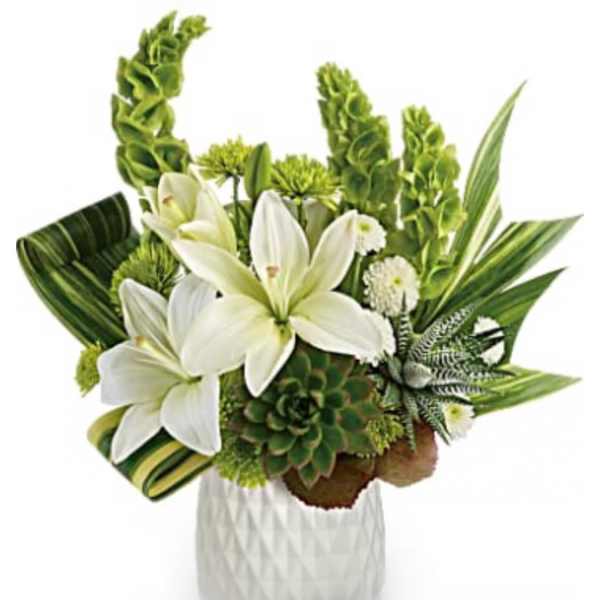 White lilies and green tropical flowers in a white vase