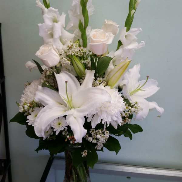White lilies and roses arranged in a clear glass vase