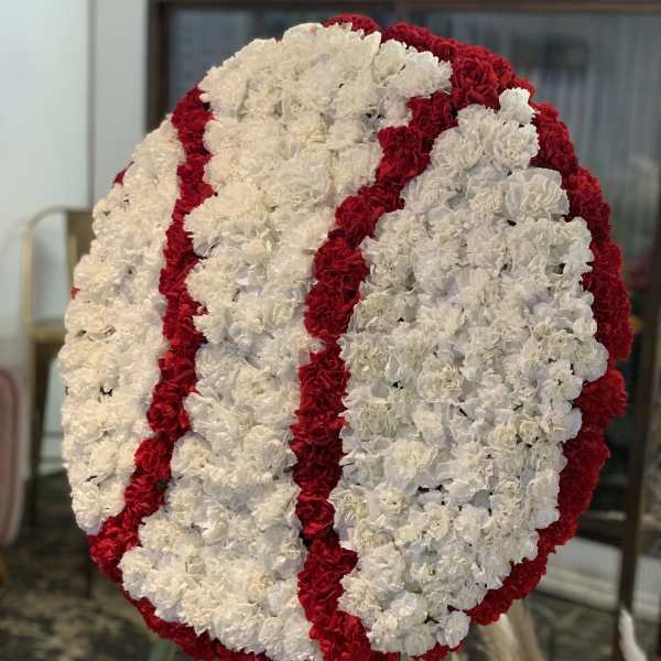 Large circular floral wreath of white and red carnations on an easel