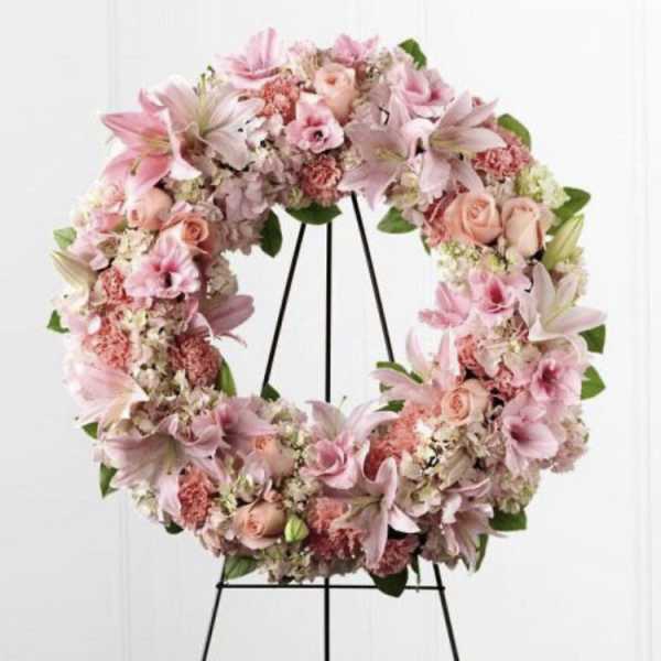 Pink floral wreath on a black stand