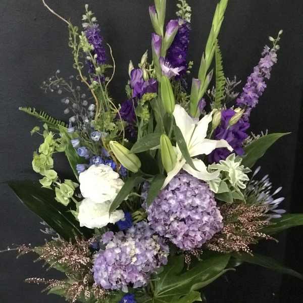 Tall bouquet of purple and white flowers with lilies and hydrangeas