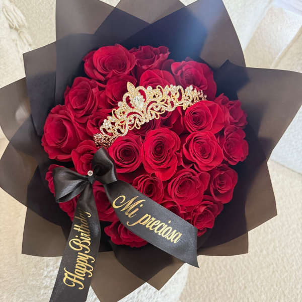 Bouquet of red roses wrapped in black paper with a tiara and ribbon