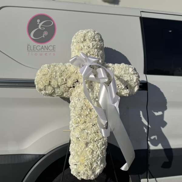 White floral cross with a silver ribbon attached to a van