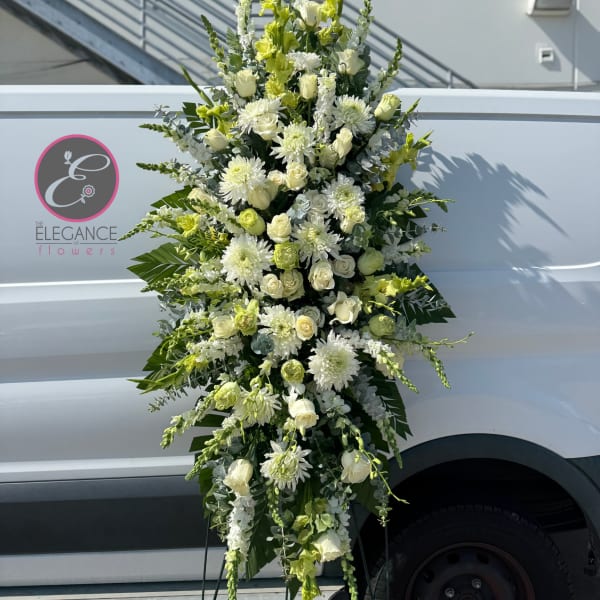 Tall white and pale green funeral spray with roses and chrysanthemums