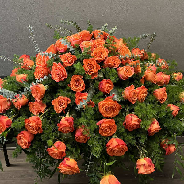 Large arrangement of orange roses with mixed greenery