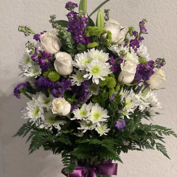 Bouquet of white roses, white daisies, and purple flowers in a glass vase