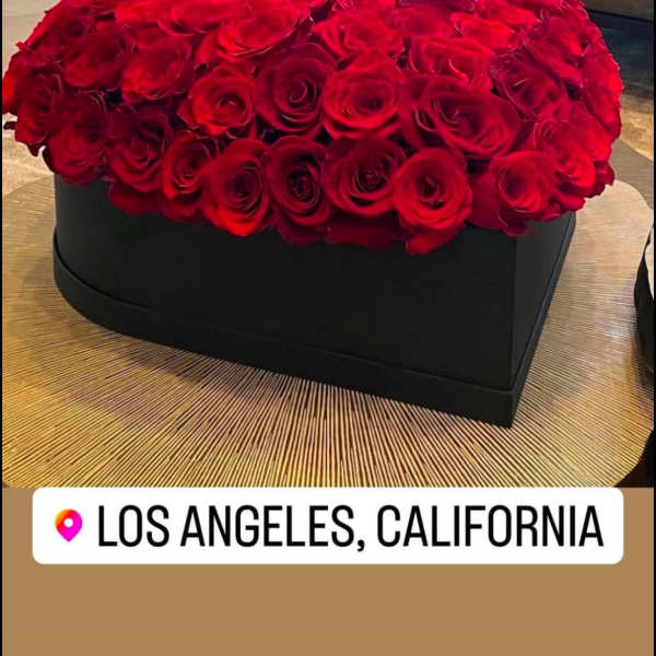 Heart-shaped black box filled with tightly packed red roses on a round table