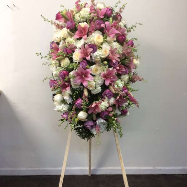 Large pink and white funeral spray on a wooden easel