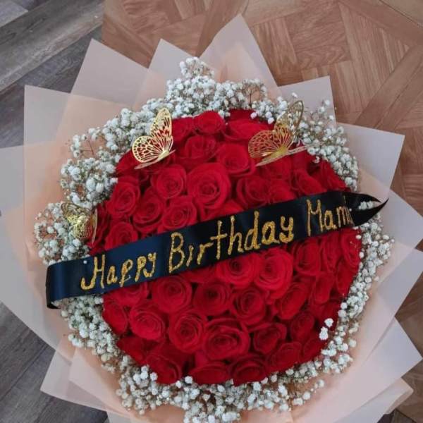 Round bouquet of red roses with white baby's breath and a birthday ribbon
