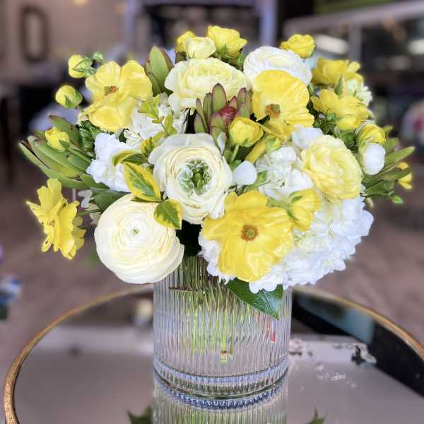 Yellow and white flower arrangement in a clear ribbed vase