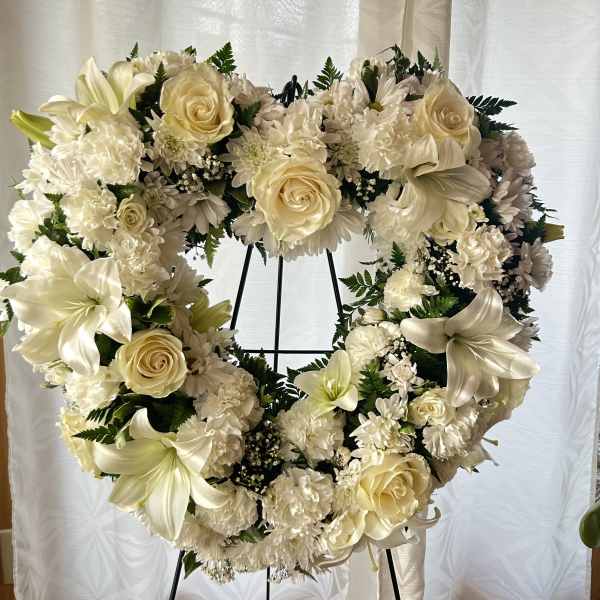 Cream floral heart wreath on a black stand