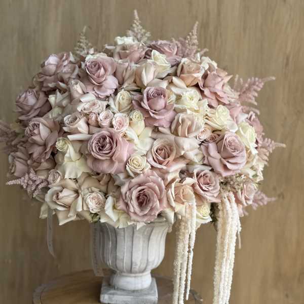 Large bouquet of blush and cream roses in a white urn vase