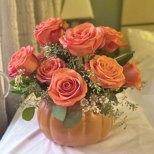 Orange roses arranged in a pumpkin-shaped vase