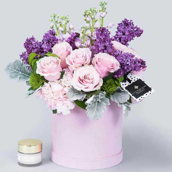 Pink roses and purple lilacs in a pastel pink hat box