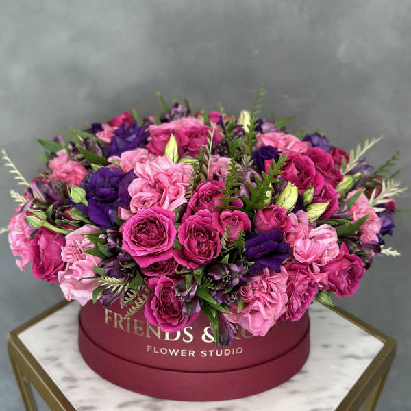 Pink and purple roses arranged in a round hat box