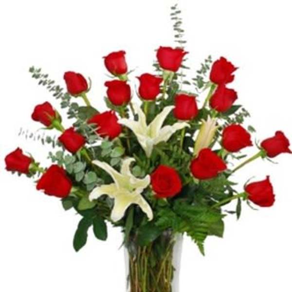 Red roses and white lilies arranged in a tall glass vase