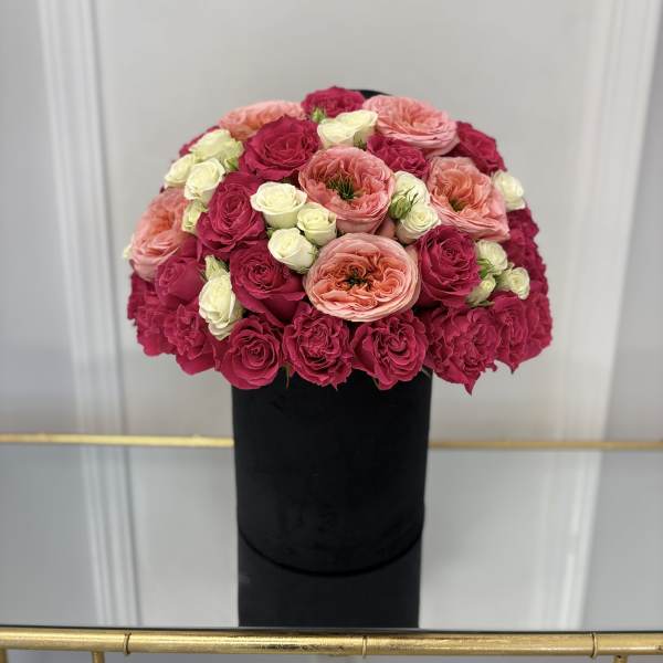 Round bouquet of pink, peach, and white roses in a black box